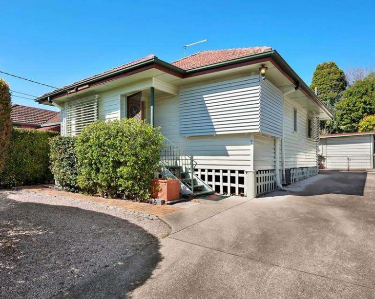 A house with a driveway leading up to it, surrounded by greenery and a clear blue sky. | Featured Image for the Investment Property Buyers Agent Brisbane service landing page